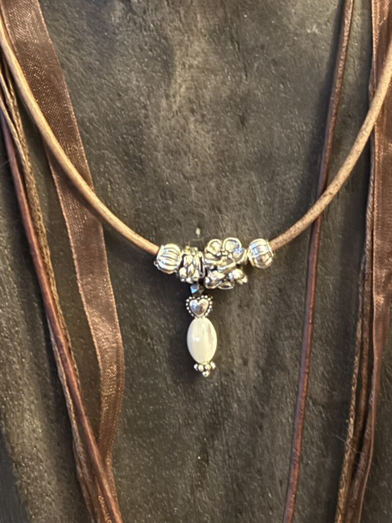 Kette mit Anhänger aus Herz, Hämatit & Süßwasserperle auf antikbraunem Lederband.