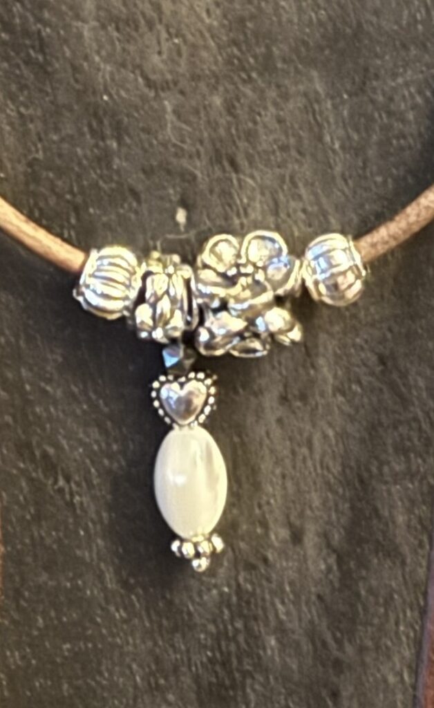 Kette mit Anhänger aus Herz, Hämatit & Süßwasserperle auf antikbraunem Lederband.